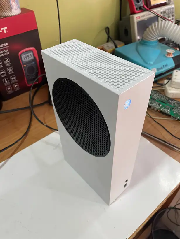 A white Xbox Series S console on the workshop bench beside test equipment.
